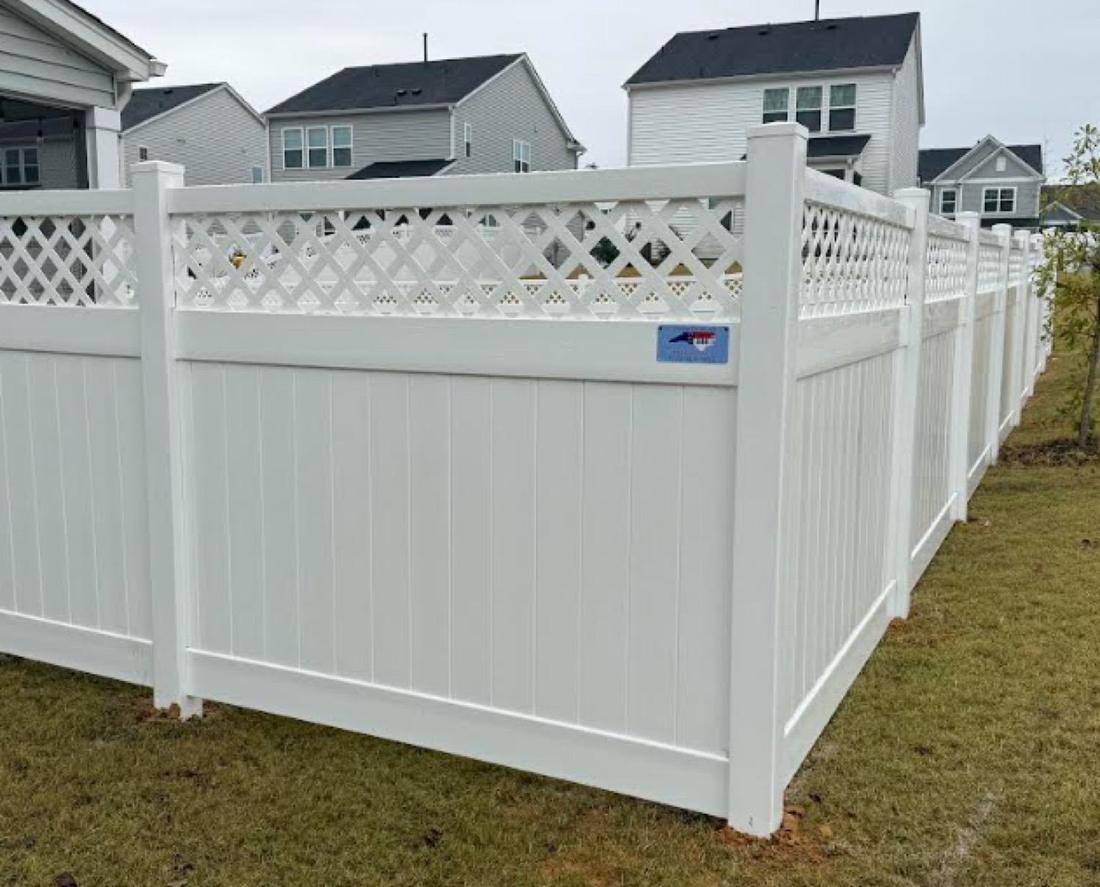 A white vinyl privacy fence with a lattice topper, running between houses.